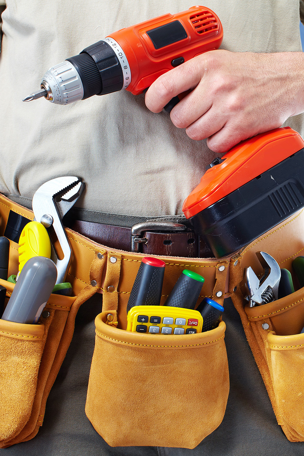 Handyman holding drill wearing toolbelt